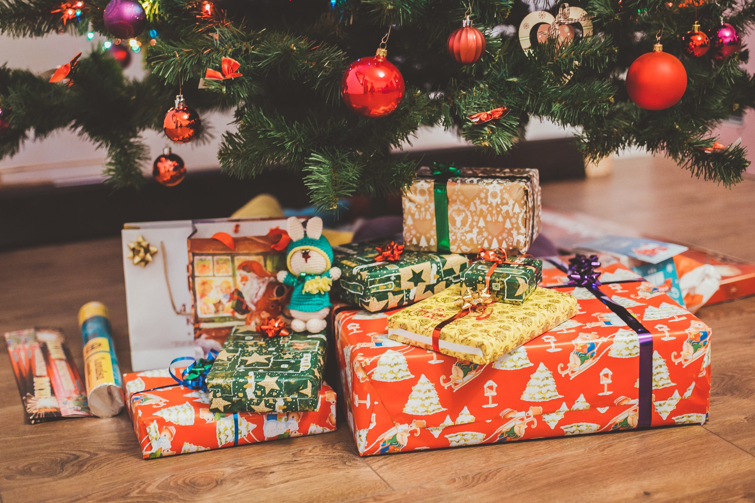 Christmas gifts wrapped underneath green tree.