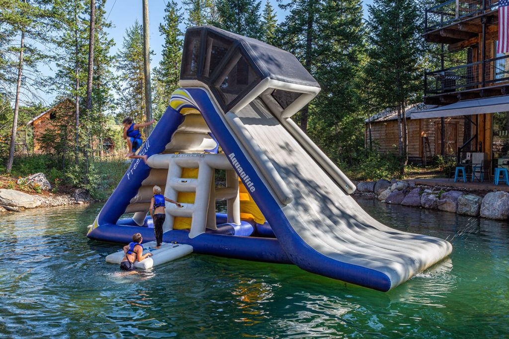 guests on glacier highline's inflatable water slide in coram, mt